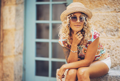 Woman wearing hat and sunglasses sitting outside