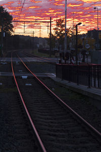 Railroad station platform against sky at sunset