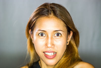 Portrait of smiling young woman against gray background