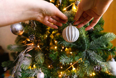 Woman hands decorating christmas tree. christmas tree with wite and silver decorations ornaments