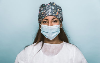 Portrait of doctor wearing mask standing against wall