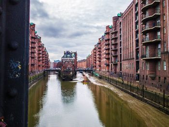 Canal amidst buildings in city against sky