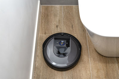 A modern robotic vacuum cleaner cleans the ceramic tiles in the bathroom next to the bath. 