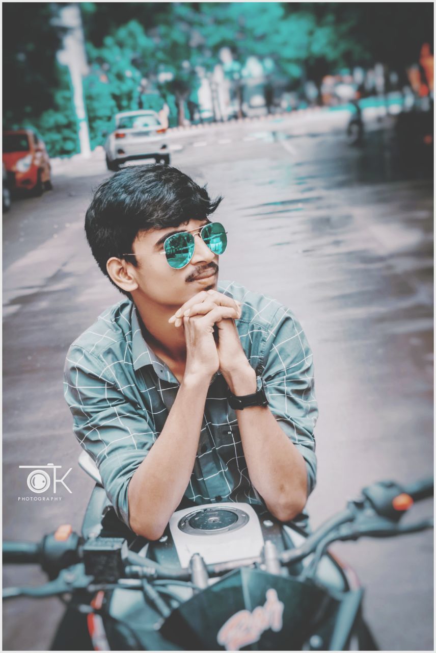 YOUNG MAN PHOTOGRAPHING WITH UMBRELLA ON ROAD