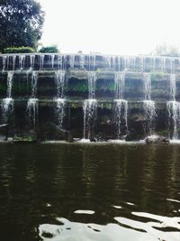 Water flowing over lake against sky