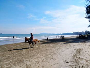 Mid adult man riding horse at beach against sky