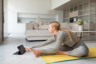 Young woman using digital tablet while sitting on sofa at home