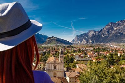 Rear view of woman looking at townscape against blue sky