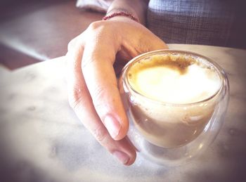 Close-up of woman holding coffee cup on table