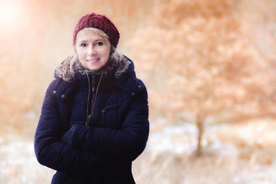 Portrait of smiling mature woman with arms crossed wearing warm clothing outdoors
