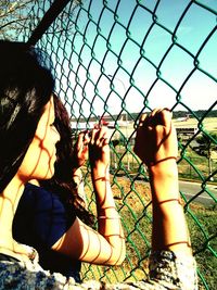Boy looking through chainlink fence