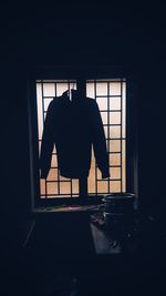 Silhouette man standing by window at home