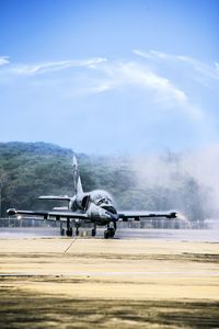 Airplane on airport runway against sky