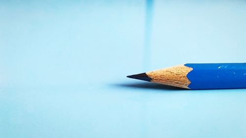 Close-up of colored pencils on table against blue background