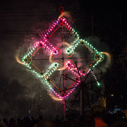 Low angle view of illuminated ferris wheel against sky at night