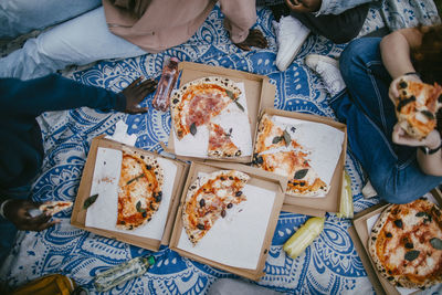 Directly above shot of half eaten pizza boxes kept on picnic blanket