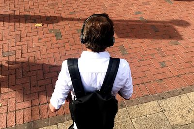 Rear view of girl standing against brick wall