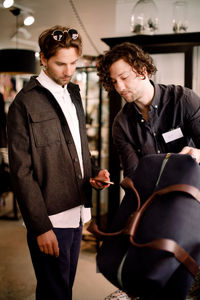 Salesman showing luggage bag to customer at retail store