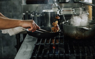 Cropped hands of person preparing food on stove