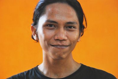 Portrait of smiling man against orange wall