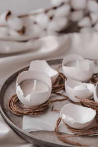 Trendy easter decorations. cracked organic eggs on plate. candle in white shell of the eggs. 