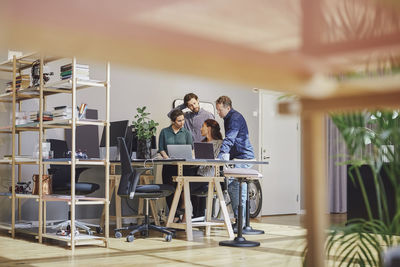 Business professionals discussing over laptop at creative office