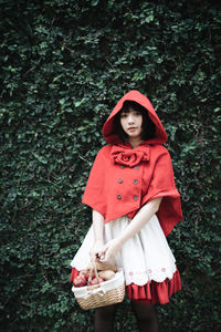 Portrait of beautiful young woman standing against red wall