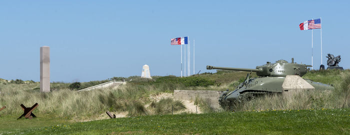 Flags on grassy field against clear sky