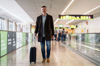 Full length portrait of young man standing at airport