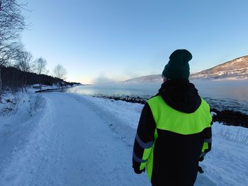 Rear view of man standing on snow covered land