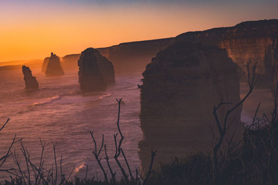 Scenic view of rock formation in sea against sky during sunset