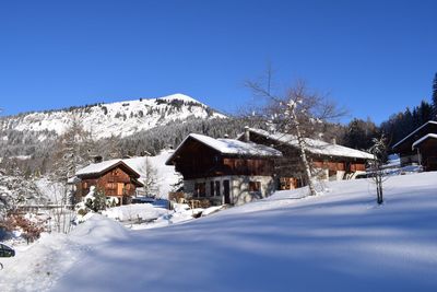 Snow covered houses and mountains against clear blue sky