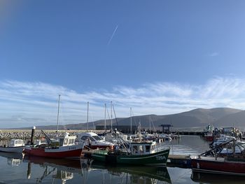 Boats moored at harbor against sky