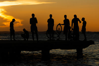Silhouette people in sea during sunset
