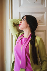 Side view of young woman drinking water at home