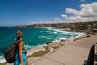 Woman walking on promenade by sea against sky