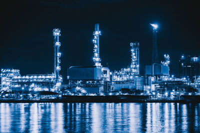 Illuminated factory against sky at night