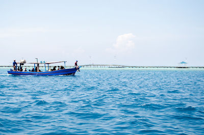 People sailing on sea against sky