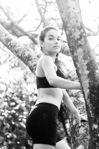 Portrait of teenage girl exercising against trees in park