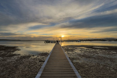 Pier over sea against sky during sunset