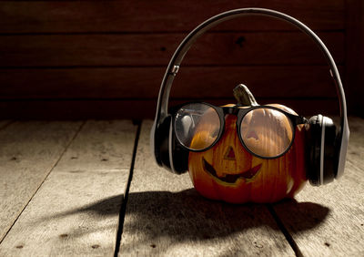 Anthropomorphic face of pumpkin wearing headphones on table