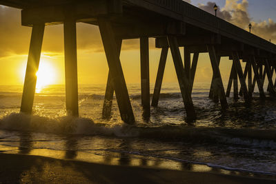 Silhouette pier over sea against sky during sunset