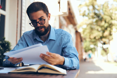 Young man reading book while sitting on table