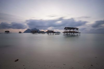 Stilt huts on sea against sky