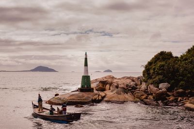 Lighthouse by sea against sky