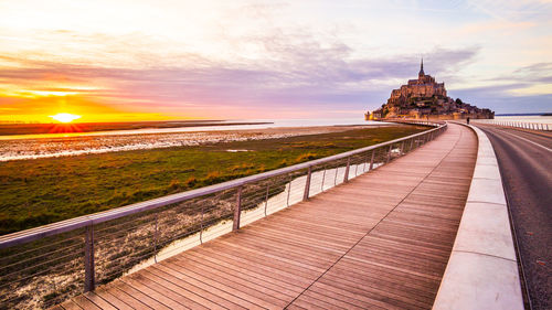 Footpath leading towards sea during sunset