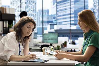Smiling friends using mobile phone while sitting at restaurant