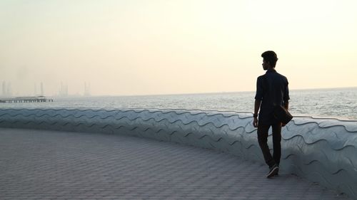 Man walking by sea against sky