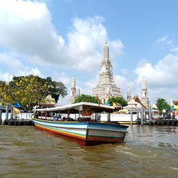 View of boats in river against cloudy sky