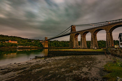 Bridge over river against cloudy sky